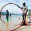 Two men stand on beach holding a red hose