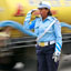 Women in blue uniform with whistle in her mouth and yellow truck driving past