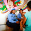 Two female officers sit in front of a colourful wall mural speaking with a woman with her back to the camera