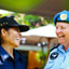 Two blue-uniformed female officers laughing with one another