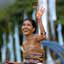 Smiling woman in colourful dress tosses flowers in the air